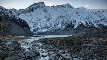 Snow-covered mountains with stream of glacial runoff.
