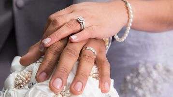 Married couple's hands clasped together showing wedding rings.