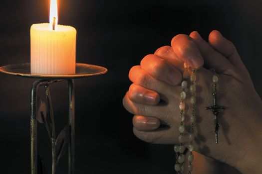 Praying the rosary in front of a lit candle