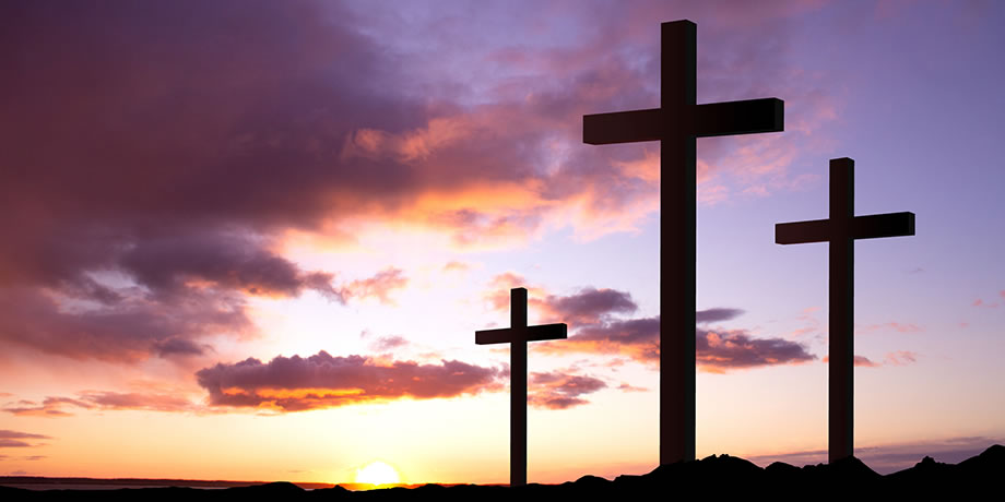 Three crosses on a mountaintop at dawn.