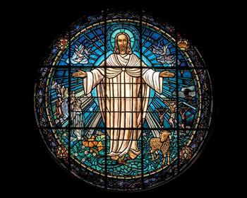 Stained glass window of Jesus with outstretched arms. 