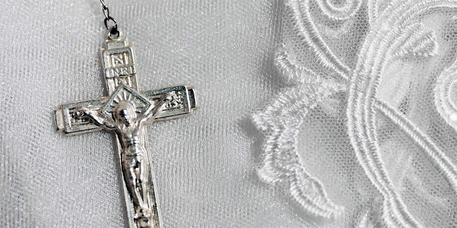 A silver crucifix of a rosary setting on white lace