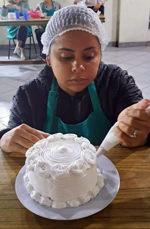 A woman decorates a cake with frosting