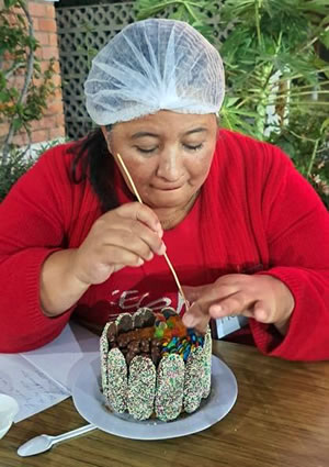 A woman decorates the top of her pastry.