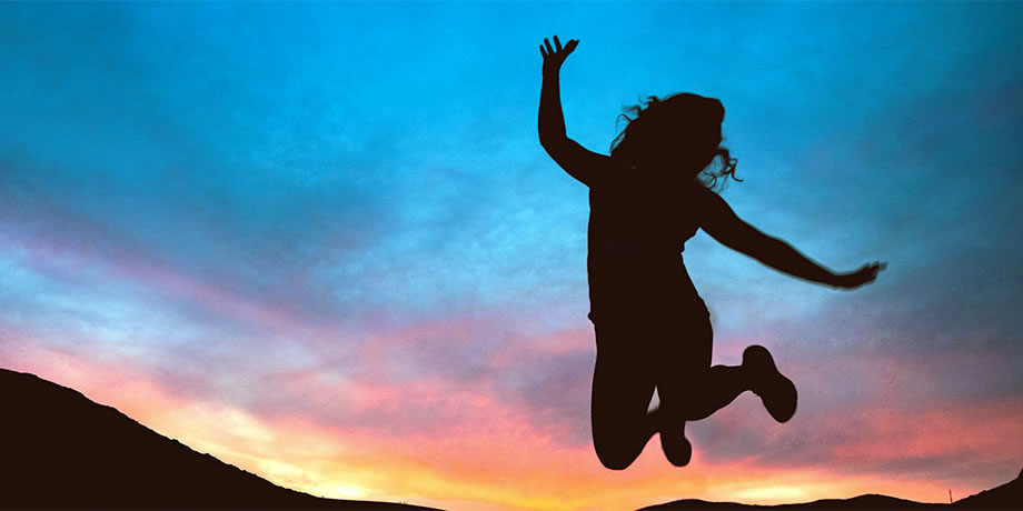 A silhouette of a girl jumping in the air at sunset 