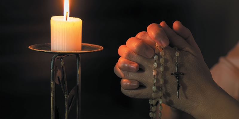 Praying the rosary in front of a lit candle