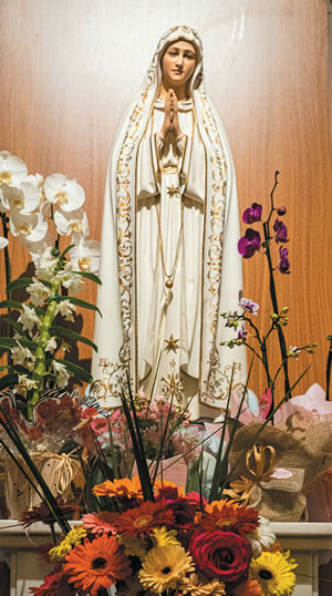 A statue of Mary surrounded by flowers