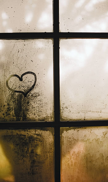 A window with heart drawn on one of the panes of glass.