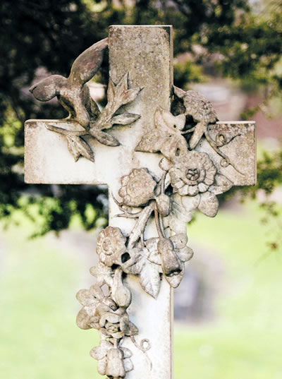 A grave marker of a cross with flowers
