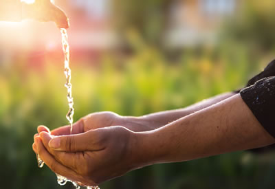 hands catch water running from a faucet