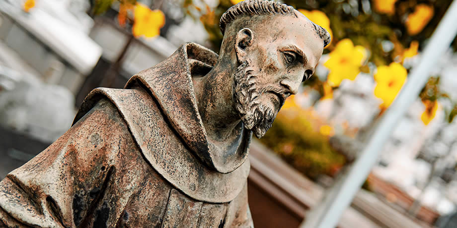 Statue of Saint Francis of Assisi with a serene expression and detailed features, holding a crucifix. São João Batista Cemetery, Rio de Janeiro, Brazil