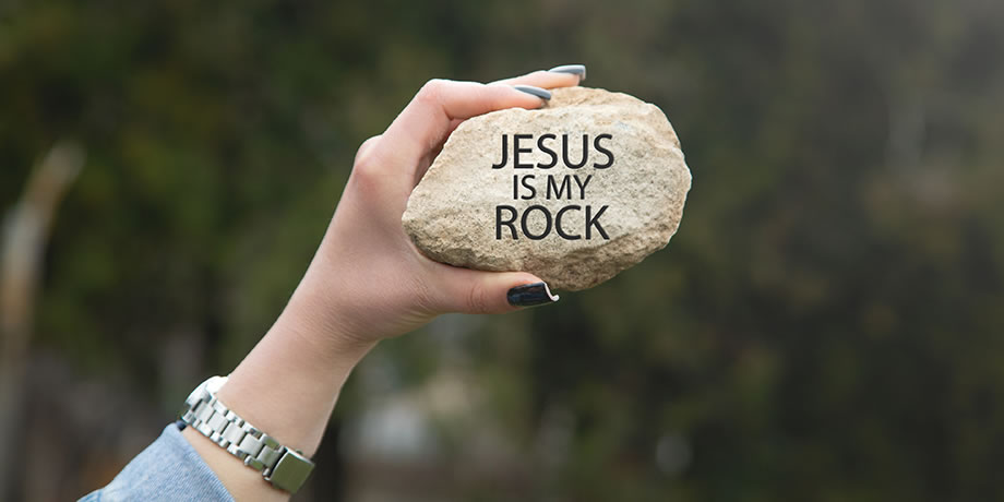 A hand holding a rock with the words Jesus Is My Rock