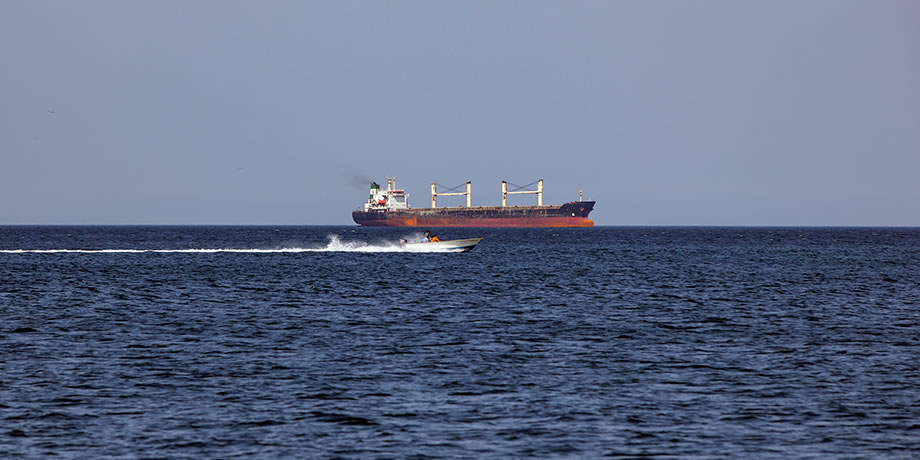 Cargo ship and speedboat in the Strait of Hormuz, Oman
