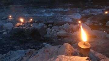 Candles sit on rocks next to a river