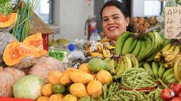 Woman looks smiling from behind her counter at a market in Fiji
