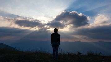 Person watching the rising sun light the darkness