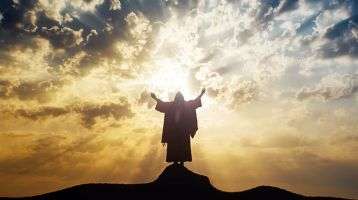 Jesus on a mountaintop with hands raised looking over the world