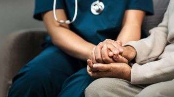 A nurse holding a patient's hand