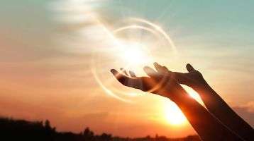 Hands raised in praise in the light of dawn.