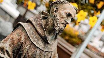 Statue of Saint Francis of Assisi with a serene expression and detailed features, holding a crucifix. São João Batista Cemetery, Rio de Janeiro, Brazil