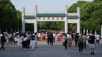 Facade of Wuhan University campus gate. With students and tourists.