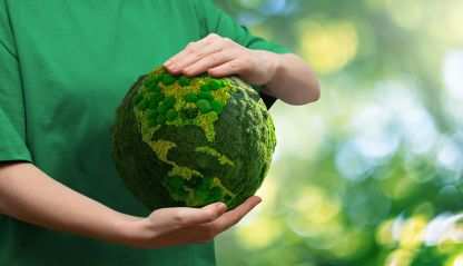 A person holds a green globe of the earth