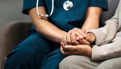 A nurse holding a patient's hand