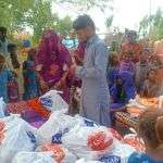 Women and children gather around food rations in a Christian village in Diki. 