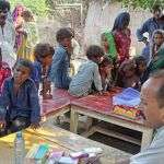 People line up to get services from the medical team in the village