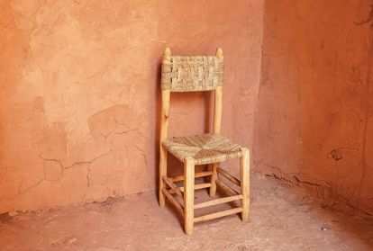 An empty chair sits in a corner surrounded by blank walls