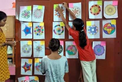 School children hanging their artwork on the wall.