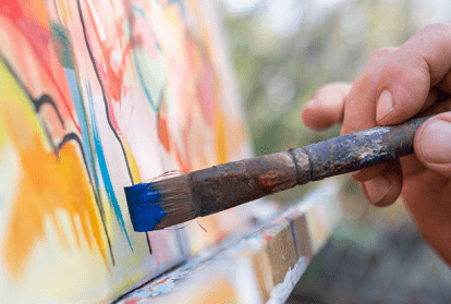 The hand of an artist painting on a canvas.
