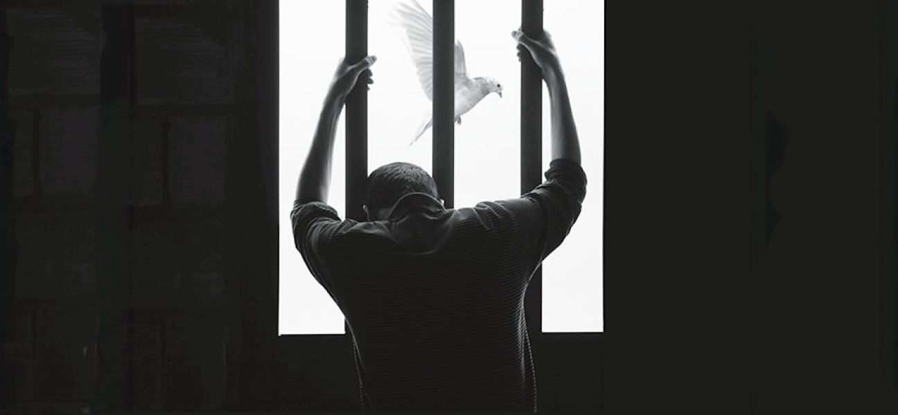 A man looking out a barred window