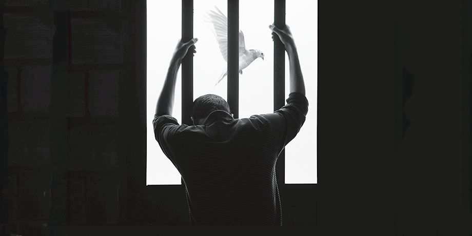 A man looking out a barred window