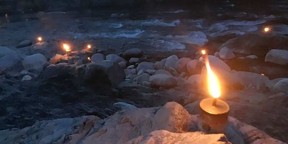 Candles sit on rocks next to a river