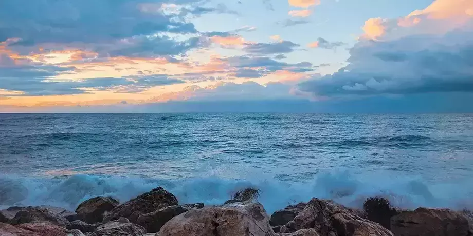 Ocean waves batter a rocky shore at dusk