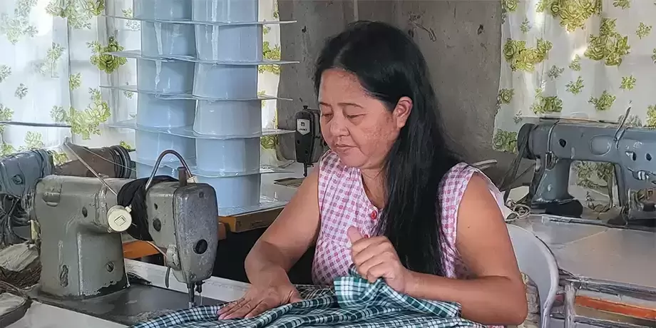 Program worker running fabric through the sewing machine.
