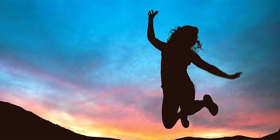 A silhouette of a girl jumping in the air at sunset 