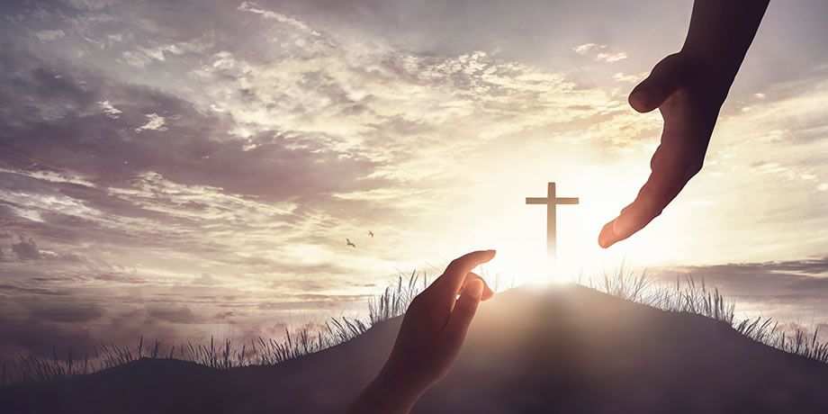Two hands reaching for each other with a light and cross in the middle