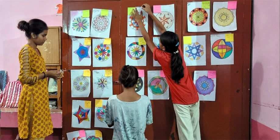 School children hanging their artwork on the wall.