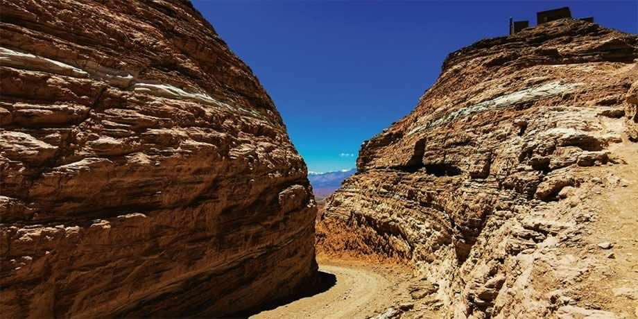 A dirt path between two stoney mountains