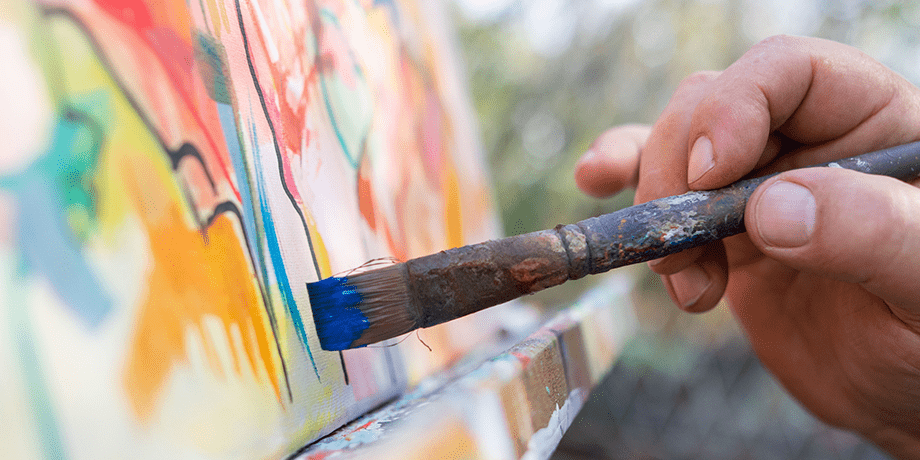 The hand of an artist painting on a canvas.