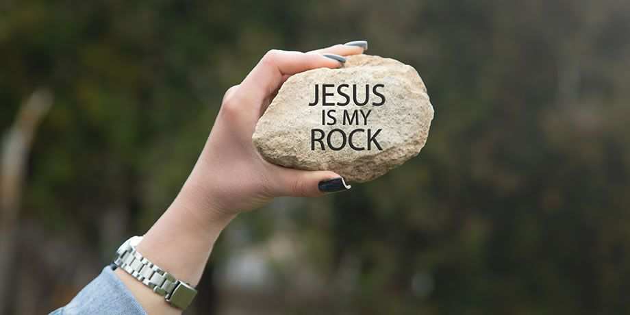 A hand holding a rock with the words Jesus Is My Rock
