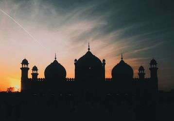 A mosque silhouetted against a setting sun
