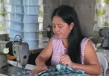Program worker running fabric through the sewing machine.