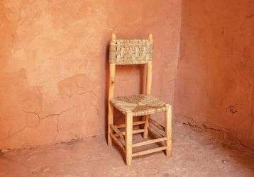 An empty chair sits in a corner surrounded by blank walls
