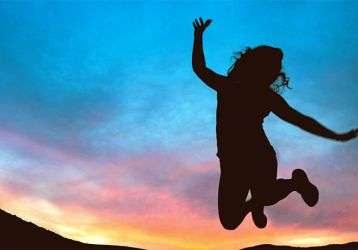 A silhouette of a girl jumping in the air at sunset 